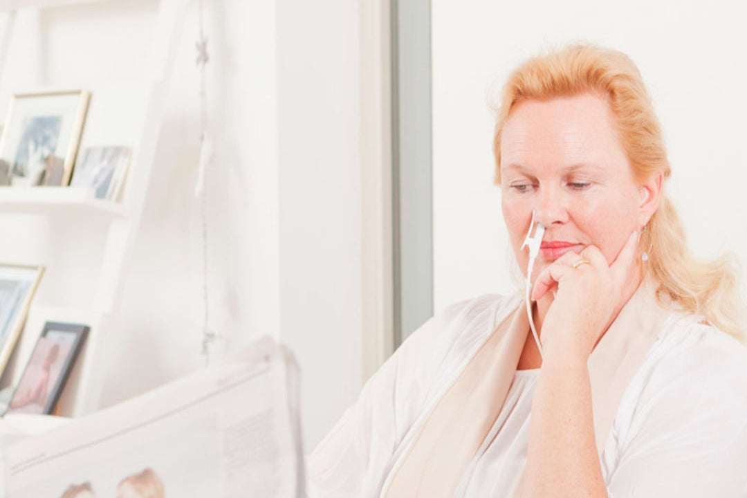 Vrouw met rood licht therapie laser in de neus aan tafel