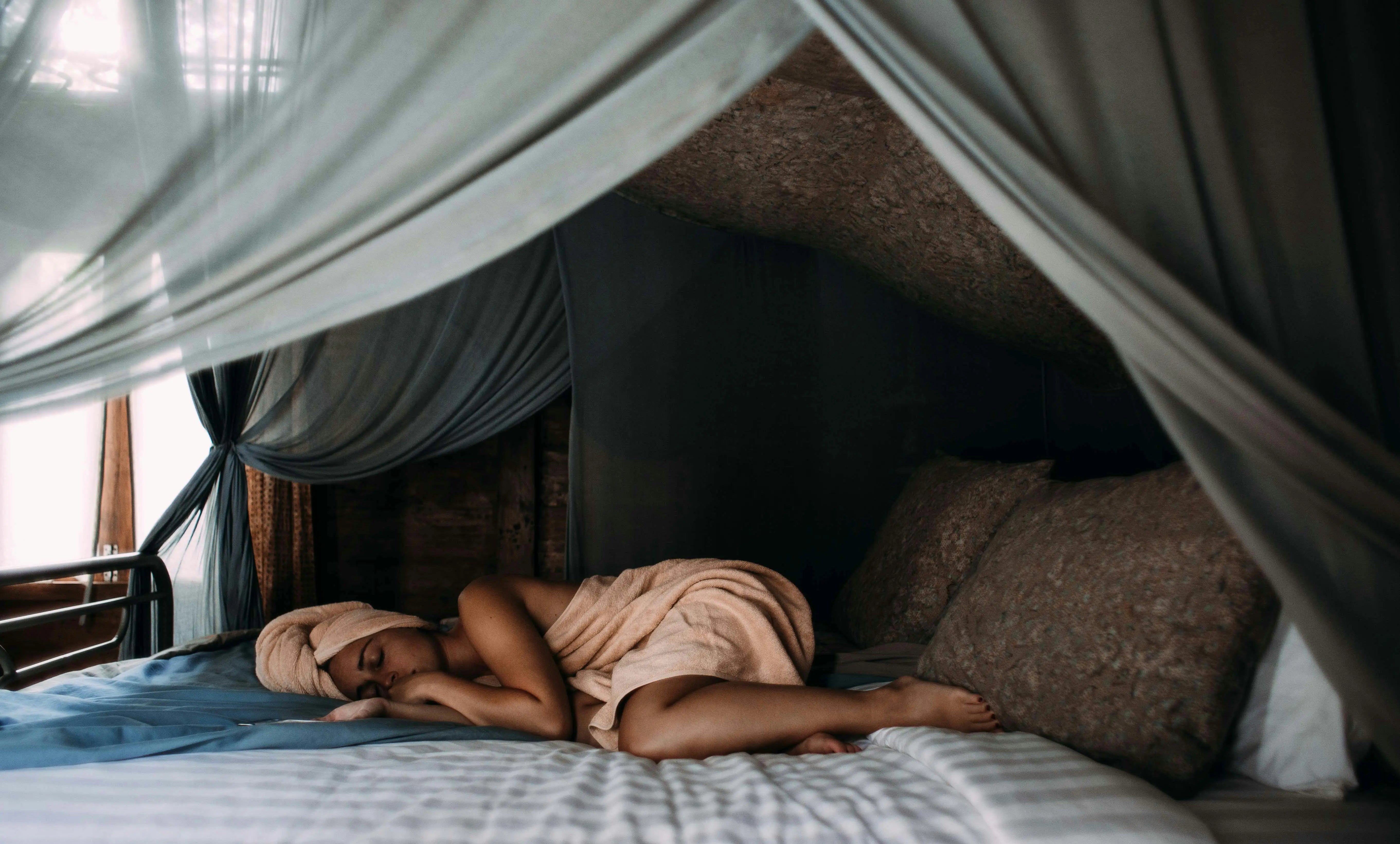 vrouw ligt op bed te slapen met handdoek op hoofd